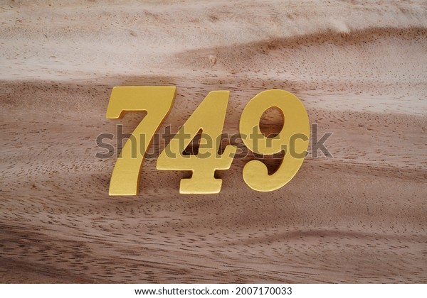 Gold Arabic numerals 749 on a dark brown to
off-white wood pattern
background.