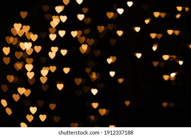 Gold background bokeh lights heart, valentine backgrounds, blurred sparkle for night backdrop. Defocused Theme of love banner. Loving, positive emotions. The concept of celebration and love.