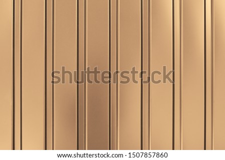 Gold background of metal wall siding, cladding. Fence with shiny, glitter. Reflecting metal convex texture. Light brown metallic striped surface. Abstract ribbed backgrounds.