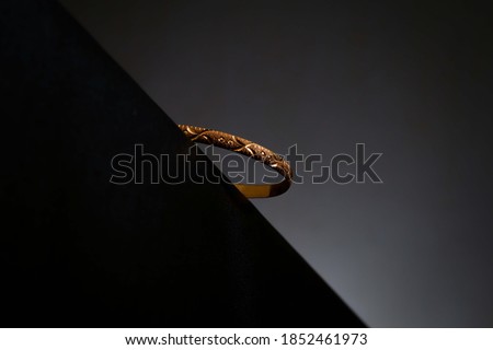 Gold bangle on edge black table with circle background light