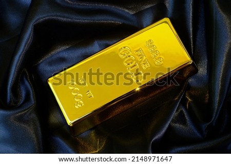 Gold bar 1 kg on smooth elegant black silk fabric luxury cloth background 