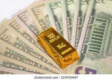 Gold Bar And American Dollars Banknotes Banknotes Are Fanned Out And Covered With A Gold Bar. Invest In Precious Metals And Save Money