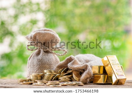 Gold bar and coin vertically aligned in the growth direction and money bag placed on wooden floor, Financial planning or savings for future spending concept.