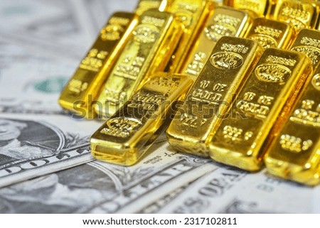 Gold bar lean against each other on the USD bills. Gold is hard commodity good, risk asset, tangible value that used to be gold reserve, and fund reserve. safe assets during war and  economic crisis. 