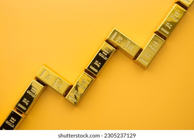 Gold bars as graph chart growing up on yellow background copy space. Gold price increase rising in commodity trading bull market investment concept. Gold is store of value in recession crisis.