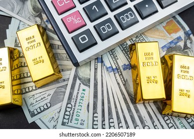 Gold Bars Lie With A Calculator Near A Large Sum Of Dollars Isolated. Concept Of Financial Savings. Gold And Dollars.