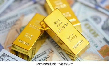 Gold bars on background of US dollars banknotes. Future gold trading and online asset trading or buying gold bars for investment - Shutterstock ID 2206508539