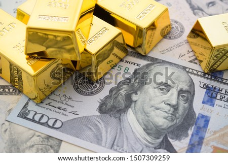 Gold bars on US dollar bill banknotes background. Concept of gold future trading, online asset commodity trading or buy gold bars for investment. It has been valued as a global currency, a commodity.