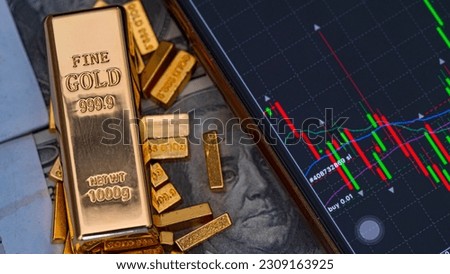 gold bars place on the phone that opens the candlestick chart. and dollar. Fluctuations in gold prices concept.