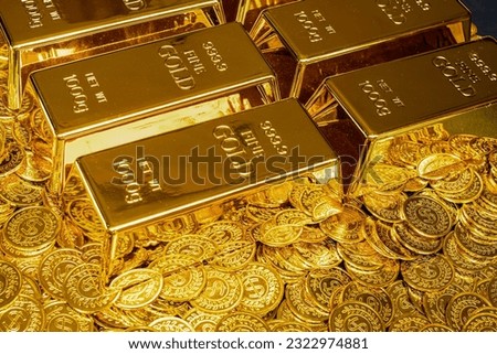Gold bars are placed on a pile of gold coins