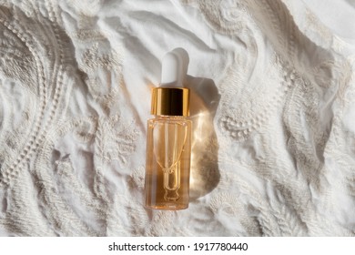 Gold Beauty Serum In A Pipette Bottle On An Ivory Fabric Regency Fashion Inspiration