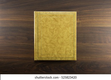 Gold Or Beige Photo Album Or Year Book Cover, Blank, Placed On A Dark Colored Wooden Table.