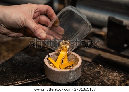 Gold being manually loaded into a crucible before melting