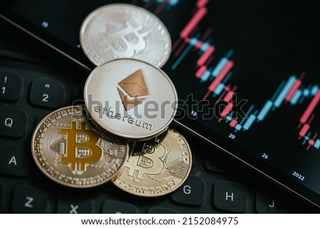 Gold Bitcoin and Ethereum cryptocurrency coins with candle stick graph chart, laptop keyboard, and digital background.