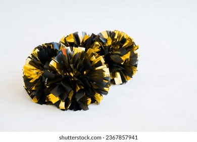 Gold and black cheerleading pom-poms on white practice mat. Background
