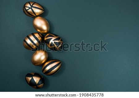 Gold, black, white eggs on a trendy emerald background. Geometry. The minimal concept. Top view. An Easter card with a copy of the place for the text.