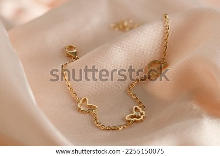 Gold  bracelet with butterflies and diamond on pink background. Romantic jewelry. Advertising still life product. 
