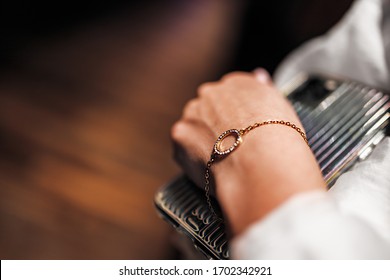gold bracelet in the form of a ring with diamonds on a chain, girl’s hand, sleeve of a white shirt, dark background.
 - Shutterstock ID 1702342921