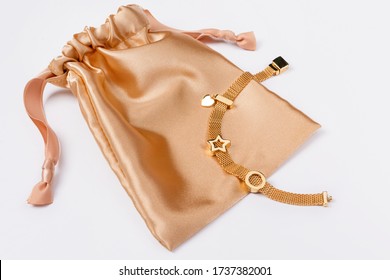 Gold Bracelet On Golden Silk Gift Bag, Jewelry Flatlay On Neutral Background. Top View Of Fashion Luxury Woman Accessories, Jewelry And Shopping Concept. Trendy Flat Lay Composition.