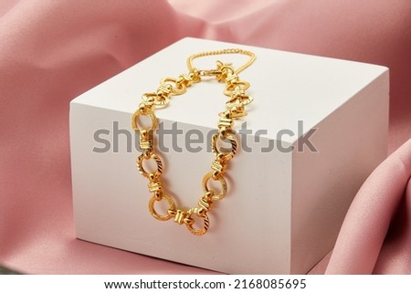 gold bracelet with white box on the pink silk background display