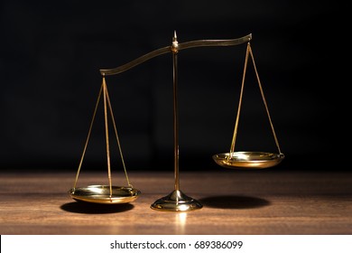 Gold brass balance scale,weight balance, imbalance scale on wooden desks with black background. - Shutterstock ID 689386099
