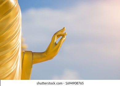 Gold buddha hand. Big buddha hand sculpture with blue sky in background. Buddha hand statue with sun light. Close up hand.