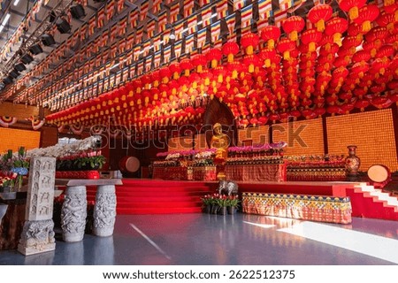 Gold Buddha statue in hall with Chinese lantern and flag decor at Longhua temple in Shanghai, China. Famous Buddhist temple of Maitreya Buddha, architectural design of Song dynasty.
