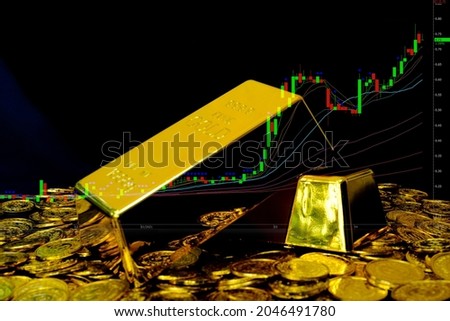 Gold bullion on pile gold coins at trading chart background
