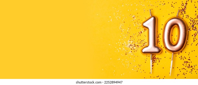 Gold candle in the form of number ten on yellow background with confetti. - Powered by Shutterstock