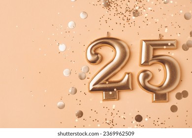 Gold candles in the form of number twenty five on peach background with confetti. 25 years anniversary celebration.