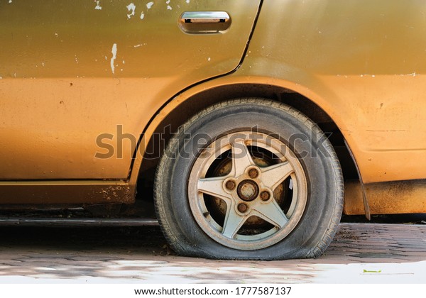 Gold car old,\
flat tire with rusty alloy\
wheel