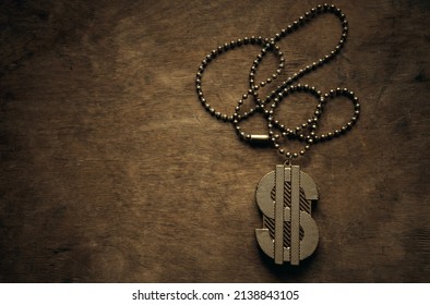 A Gold Chain With A Dollar Sign On A Wooden Table In Vintage Style. Gangster Jewelry On A Chain. The Dollar Symbol In Gold.