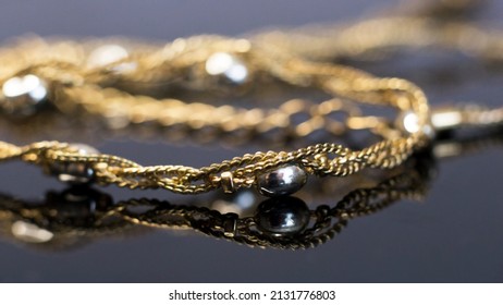 Gold Chain On A Black Mirror Surface