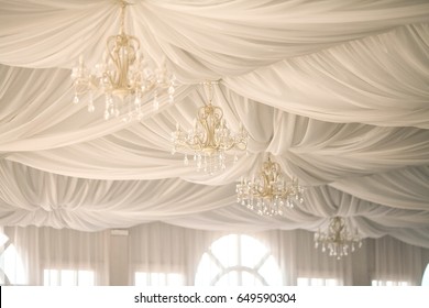 gold chandeliers on an tent's ceiling in a wedding party. wedding decor in a white tent.