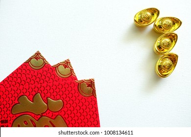 Gold Chinese money and red envelope on white background. Chinese text on envelope meaning good fortune and happiness. Chinese new year festival.