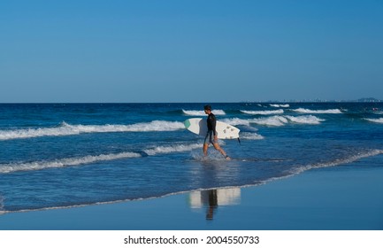 GOLD COAST, AUSTRALIA - APRIL 16, 2018: Surfers carrying surfing boards on Main Beach at Surfers Paradise. One of the main tourist destination at Gold Coast.
