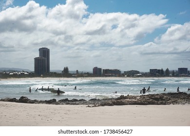 Gold Coast, Queensland, Australia - Dec 31 2019: Holiday Mood in Currumbin Beach. Surfing, swimming and enjoying city view.