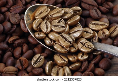 Gold Coffee Beans On A Pile Of Coffee Beans. The Concept Of Luxury Is Extraordinary. Coffee Beans In A Spoon. Golden Coffee Beans