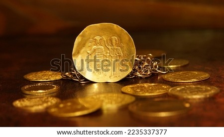 Gold coin histamenon 13th century Byzantium on the background of vintage gold coins and chains selective focus money abstraction