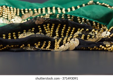 Gold Coins Draped And Hung Over Green And Black Sheer Fabric With Room In Front For Text On Black Foreground