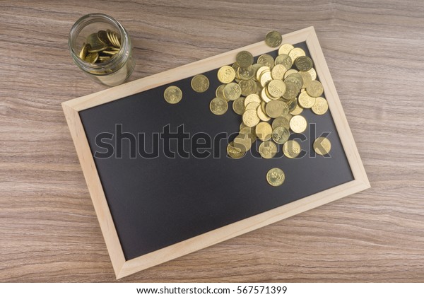 Gold\
coins in glass jar on chalkboard. Financial\
concept.