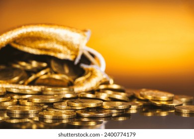 Gold coins in sack. Gold money on orange background. Copy space. A pile of coins. A bag with gold coins. Treasure hunt