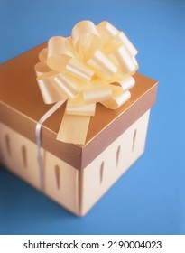 Gold Colored Gift Box With Ribbon On Blue Background