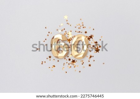 Gold colored number 60 and stars confetti on a blue background. Festive creative concept.