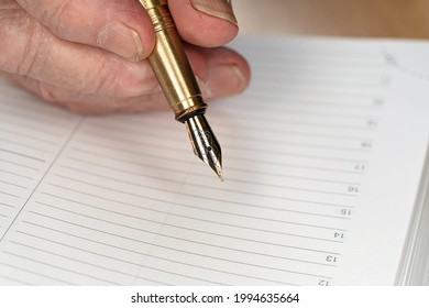 Gold Coloured Fountain Ink Pen In Senior Woman Hand About To Write Something On Empty Daily Planner Page, Closeup Detail