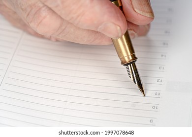 Gold Coloured Fountain Ink Pen In Senior Woman Hand About To Write Something On Empty Daily Planner Page, Closeup Detail