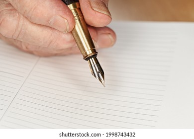 Gold Coloured Fountain Ink Pen In Senior Woman Hand About To Write Something On Empty Daily Planner Page, Closeup Detail