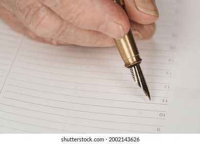 Gold Coloured Fountain Ink Pen In Senior Woman Hand About To Write Something On Empty Daily Planner Page, Closeup Detail