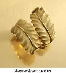 Gold Cuff Bracelet In Leaf Motif On Reflective Gold Surface