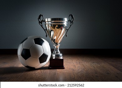 Gold Cup Trophy And Soccer Ball On Hardwood Floor, Winning Concept.